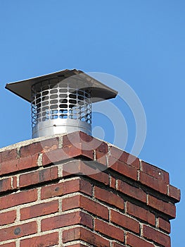 Single Flue Chimney Cap Close up Atop a Red Brick Chimney