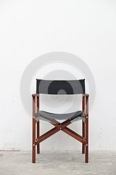 Single folding wooden director chair on white cement wall background
