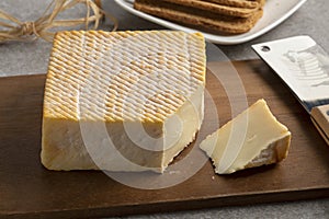 Single French Le Carre du Pere Antoine cheese and a piece on a cutting board