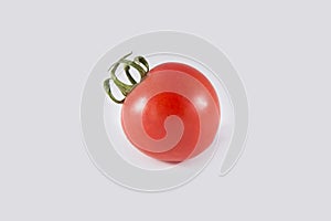 A single cherry tomato on a white background. Close-up photo