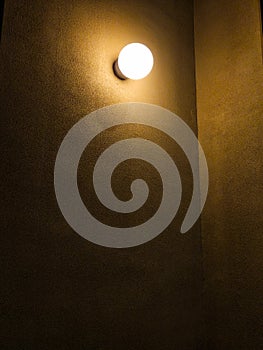 Single Glowing Light Bulb on Dark Textured Wall