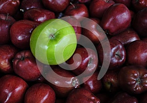 Single Green Apple with Bunches of Red Apples