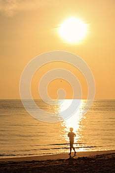 Single guy jogging with bare feet on beach
