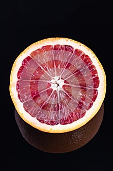 Single half of a blood orange isolated on black