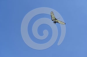 A single hang glider against a clear blue sky.