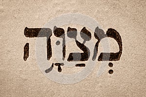 Single hebrew word Mitzvah on page of old Torah book. English translation is commandment. Hebrew script. Closeup