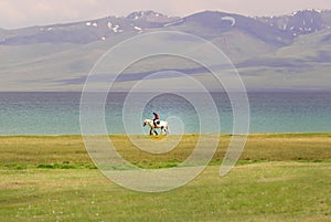 Single horse rider riding by the Song Kol lake