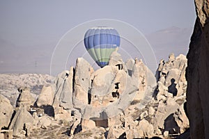 Single Hot Air Balloon rising over ancient cave dwelling in Goreme Cappadocia.