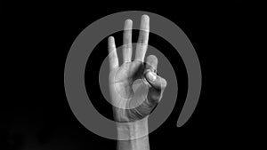 A single human hand comes up and shows good luck and an okay gesture or ring gesture isolated on a black background. Easy chroma k
