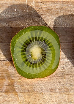 Single kiwi slice on a wooden board