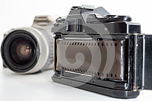 Single lens reflex camera and a film roll on white background