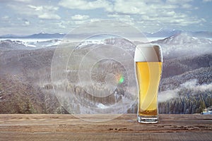 Single light beer in glass and landscape of mountains on background