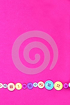 Single lines of buttons on a pink paper background