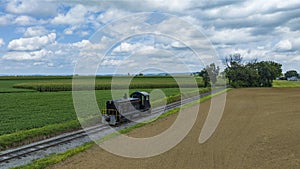Single Locomotive Traversing Along Railway Tracks Bordering A Plowed Field And Green Crops