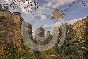 Single lone autumn leaf hanging in front of Meteora landscape, Greece