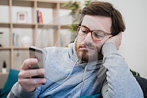 Single lonesome man checking mobile phone on the couch photo