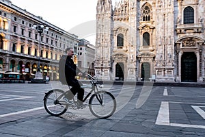 Single man on bicycle riding in empty square of Milan`s Cathedra