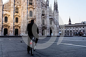 Single man on bicycle standing alone in front of Milan`s Cathedr