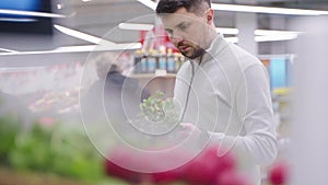 single man is buying greenery in supermarket