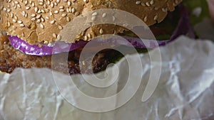 Single man unwrapping and eating hamburger home, overweight concept, closeup