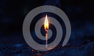 A single matchstick is lit in the dark