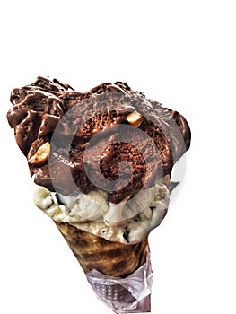 Single melting chocolate and vanilla chips ice cream scoop flavor in waffle cone in hand holding on white