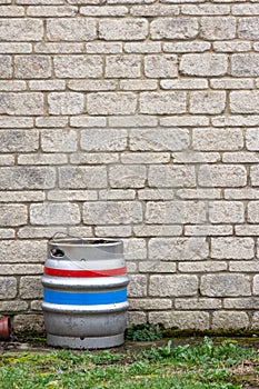Single metal beer barrel against a light stone brick wall