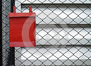 single metal red mailbox hanging on chain link fence