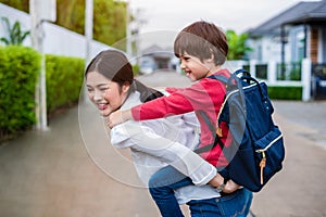 Single mom carrying and playing with her children near home with villa street background. People and Lifestyles concept. Happy