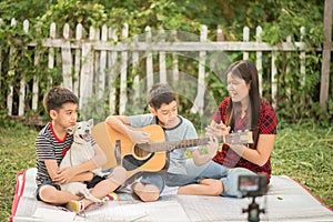 Single mom and sons play guitar together in the park