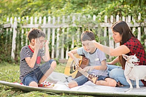 Single mom and sons play guitar together in the park