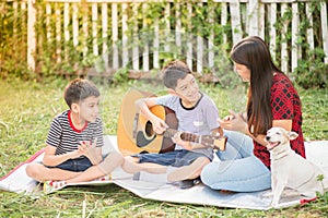 Single mom and sons play guitar together in the park