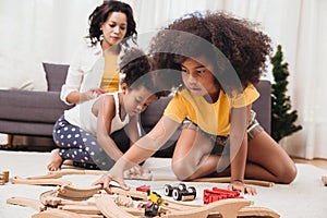 Single mom with two daughter playing toy in apartment. Nanny looking or childcare at home black people