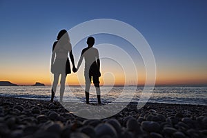 Single mother on the beach with son at sunrise