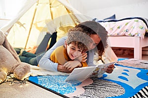 Single Mother Reading With Son In Den In Bedroom At Home