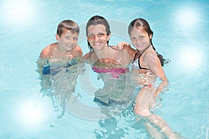 Single mother with son and daughter play in pool summer