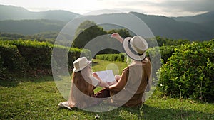 single mother is spending time with her child in garden, teaching to draw