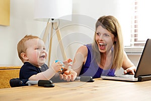 Single mother working on laptop with her baby boy at home