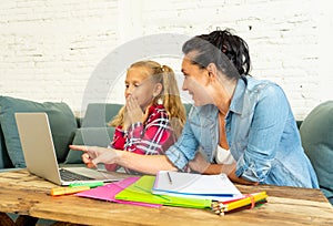 Single mum helping her daughter doing her homework with laptop at home