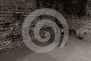 Single, old chair against old brick wall - black and white photo