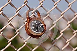 A single old rusty lock on a chain link fence
