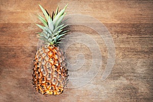 Single one full whole organic pineapple fruit on wooden background ripe fully grown mature, laid down on its side negative empty s