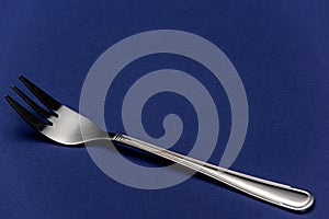 Single One Stainless Steel Fork on Blue Background. Detail Close Up View