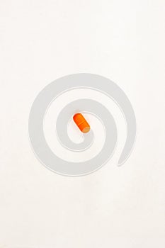 Single orange pill on white background. Childrens antipyretic concept. Close up top view