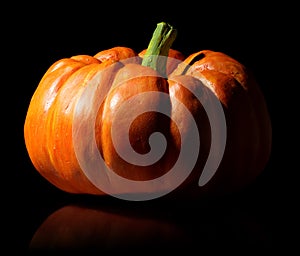 Single orange pumpkin on black