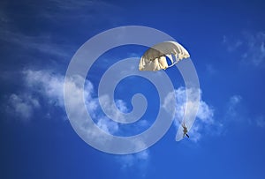 Single parachute jumper against blue sky background