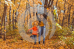 Single parent family playing with autumn leaves in park. Happy mom and son throw autumn leaves up in fall park.