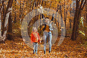 Single parent family playing with autumn leaves in park. Happy mom and son throw autumn leaves up in fall park.