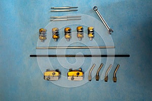 Single parts of a surgical hand fixator lie on a blue surgical cloth