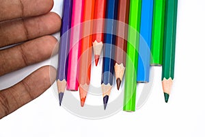 Single person arranging some different colored wood pencil crayons on a white background